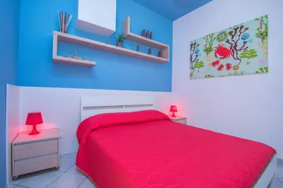 a bedroom with a red bed and blue walls at Il Muretto in Lascari