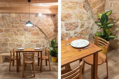 a dining room with a table and a stone wall at Loft Vetriera in Palermo
