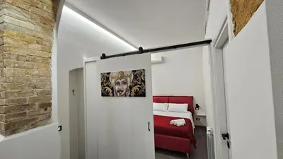 a room with a bed and a red couch at Suites Masculu & Fimmina in Palermo