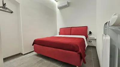 a bedroom with a red bed and a red couch at Suites Masculu & Fimmina in Palermo
