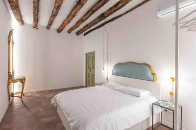 a bedroom with a white bed and a wooden floor at Calderai 82 suites 1 e 2 in Palermo