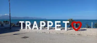 a sign that says happier in front of the ocean at Gravina in Trappeto