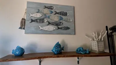 a painting of fish on a wall above a shelf at Casa Tequi a 200mt dal mare in Terrasini