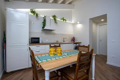 a kitchen with a table and chairs and a kitchen with a refrigerator at Cortile Del Greco Apartments in Palermo
