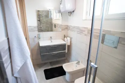 a white bathroom with a sink and a toilet at Appartamento con terrazza in Isola delle Femmine