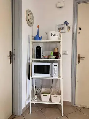 a white shelf with a microwave on top of it at Isola delle Femmine Holiday Nancy in Isola delle Femmine