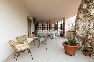 a living room with chairs and tables and a stone wall at Isola delle Femmine Holiday Nancy in Isola delle Femmine