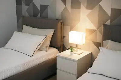 a bedroom with two beds and a table with a lamp at La Casa di Ale in Palermo
