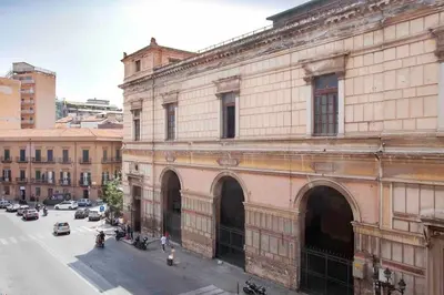 an old building on a street next to a street with cars at The house Politeama Palermo Historic center in Palermo