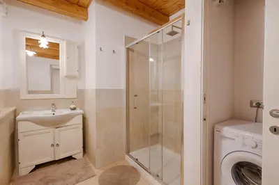 a bathroom with a shower and a sink and a washing machine at GuestHost - Il Piccolo Scrigno - Functional & Central Studio in Castellammare del Golfo