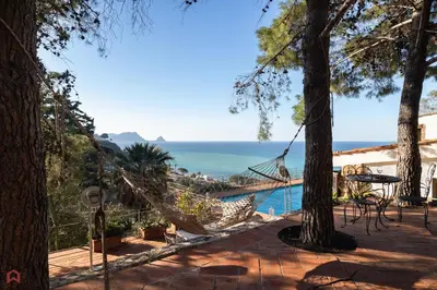 a patio with a hammock and a view of the ocean at Stunning seaview villa in Altavilla Milicia