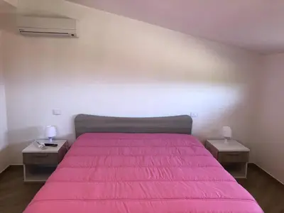 a bedroom with a pink bed with two night stands at Scopello Guidaloca Villas in Scopello