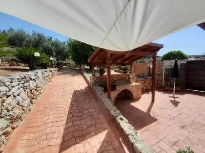 a patio with an umbrella and a stone wall at Mediterraneo in Castellammare del Golfo
