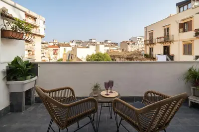 a patio with three chairs and a table on a balcony at Conte Ruggero Apartment by DomuSicily in Palermo