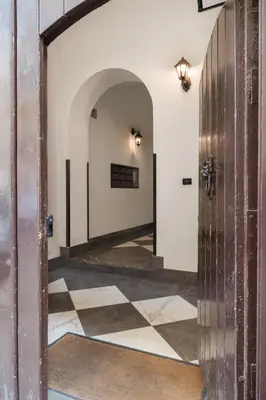 an open door to a hallway with a checkered floor at Conte Ruggero Apartment by DomuSicily in Palermo