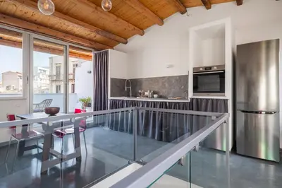a kitchen and dining room with a stainless steel counter top at Conte Ruggero Apartment by DomuSicily in Palermo