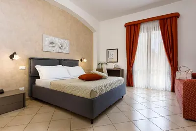 a bedroom with a bed and a window with red curtains at Hotel La Darsena in San Vito lo Capo
