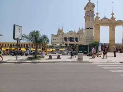 a building with a clock tower and people walking on the street at GIORGISA in Palermo