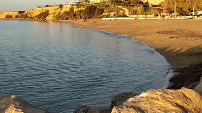 a beach with rocks and people on the beach at Phoenix Apartment in Terrasini