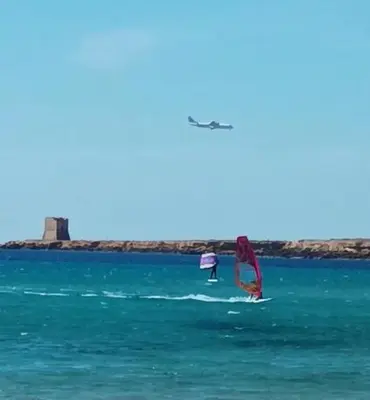 two people are windsurfing in the ocean at Phoenix Apartment in Terrasini