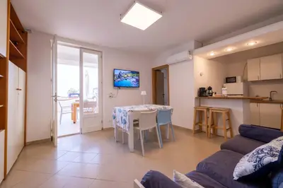 a living room with a table and a kitchen at Apartment on the Beach - Large Terrace in Alcamo