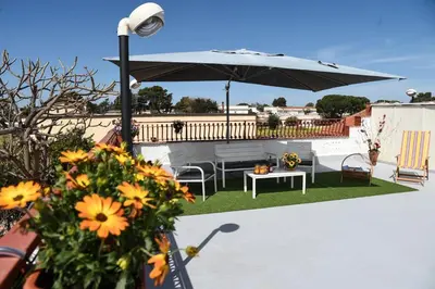 a patio with a table and an umbrella and flowers at Villa Rosetta vacanze al mare in Carini