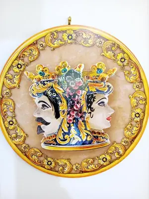 a gold plate with two women wearing a tiara at Villa Rosetta vacanze al mare in Carini