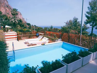 a swimming pool with two lounge chairs and a fence at Sea apartment & pool 2 in Palermo