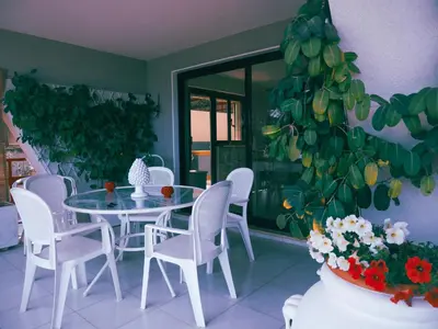 a dining room with a table and chairs and a plant at Sea apartment & pool 2 in Palermo