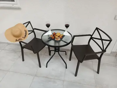 a table with two chairs and two glasses of wine at Clio's House - Mondello in Mondello