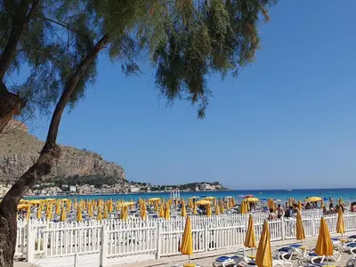 a beach with chairs and umbrellas and the ocean at La Casetta del Melograno in Mondello