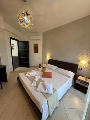a bedroom with a large bed and a chandelier at La Chiocciola 2 Bed&Breakfast in Castelluzzo