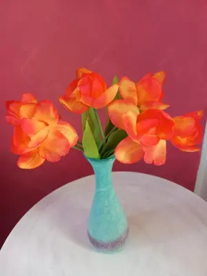 a green vase with orange flowers on a table at La Chiocciola 2 Bed&Breakfast in Castelluzzo
