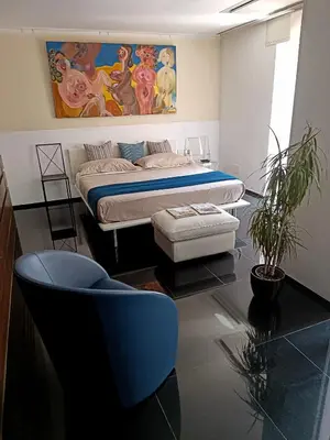 a bedroom with a bed and a blue chair at Luxury suite 2 min dal Politeama - Free Parking in Palermo