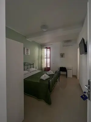 a bedroom with a green bed and a television at B&B Marco Polo in Terrasini