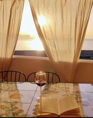 a glass of wine and an open book on a table with a window at Casa del Pescatore Terrasini in Terrasini