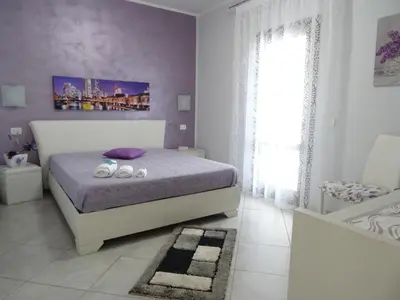 a bedroom with a bed with purple walls and a window at B&B Le Onde Del Mare in San Vito lo Capo