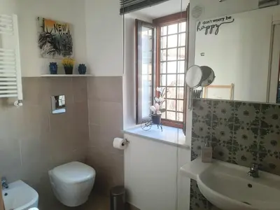 a bathroom with a toilet and a sink and a window at Peri Peri House - Palermo Centro in Palermo