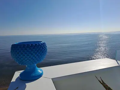 a blue vase sitting on a ledge next to the ocean at Blue Life, sea-luxury rooms on the beach between Palermo and Cefalu' in Casteldaccia