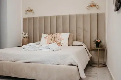 a bedroom with a white bed with a large headboard at Borgo La Chiusa in Cinisi
