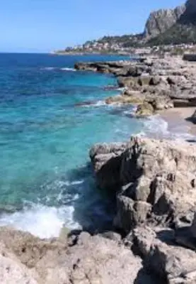 a beach with rocks and the blue water at CasALE Sampó in Palermo