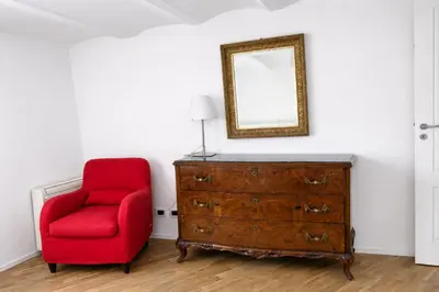 a red chair sitting next to a dresser with a mirror at Palazzo Moncada appartamento 2 in Palermo