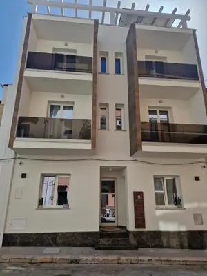 a large white building with windows and doors at The waves in Terrasini