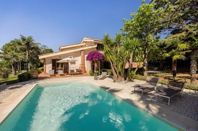 a swimming pool with two chairs and a house at Cleo - Villa Siciliana in Partinico