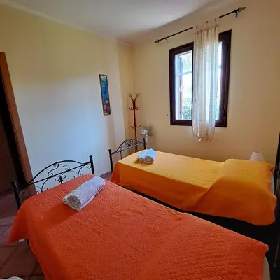 two beds in a room with orange sheets at PTA Appartavilla in Campofelice di Roccella