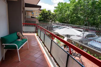 a balcony with a green chair and an umbrella at Gardenia Home in Palermo