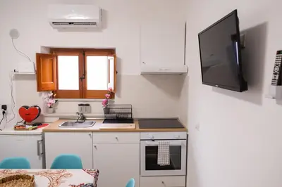 a kitchen with a tv on the wall next to a counter at Matilde’s Holiday House in Terrasini