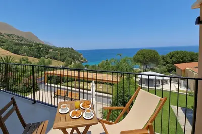 a table and chairs on a balcony with a view of the ocean at Casa Richilde in Scopello