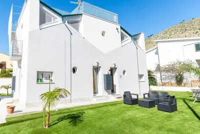 a white house with a green lawn at 3B Mondello Apartments in Palermo