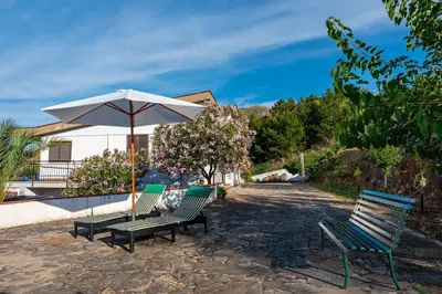a group of chairs and an umbrella on a patio at Villa Duca Country House in Castellammare del Golfo